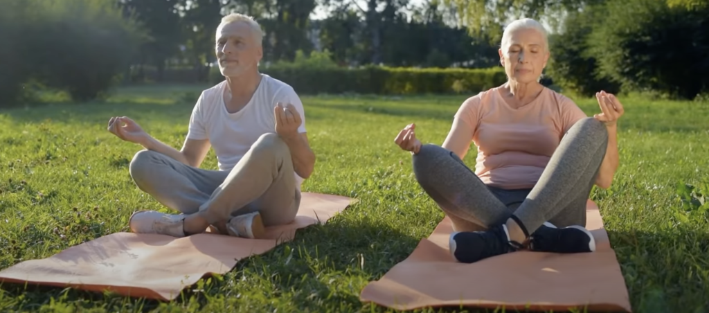 a senior man and woman doing yoga outside