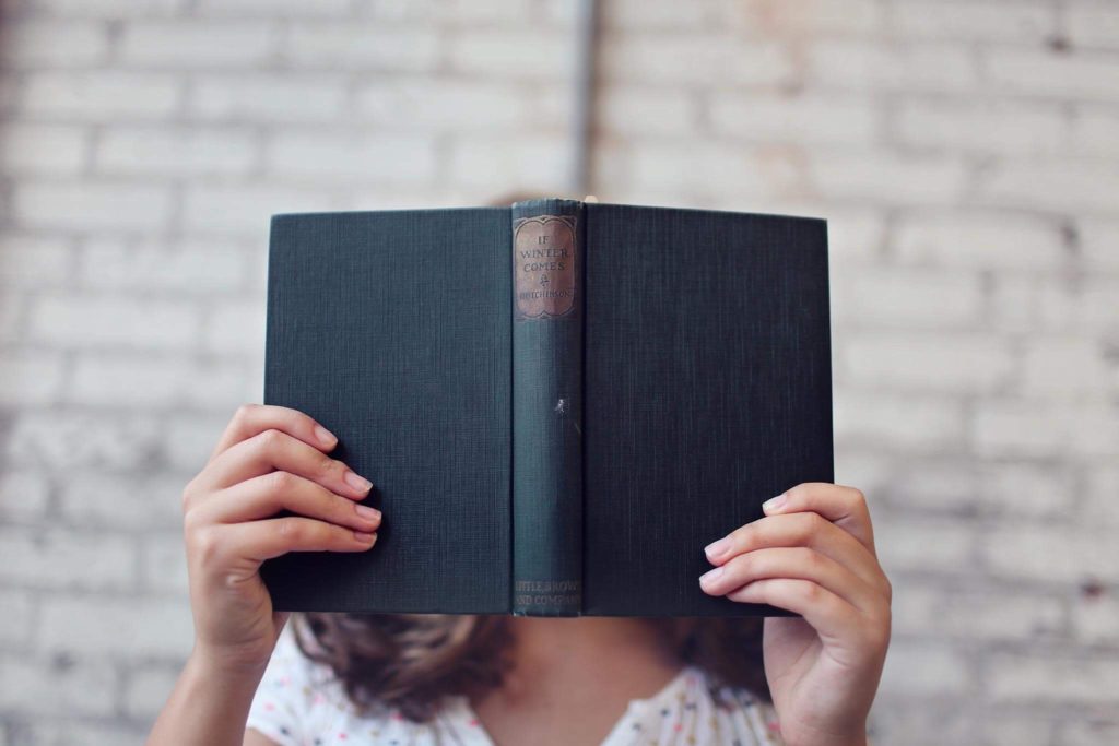 woman holding a book infront of her face