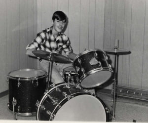 A 1960s photo of a teenager posing with a new drum kit
